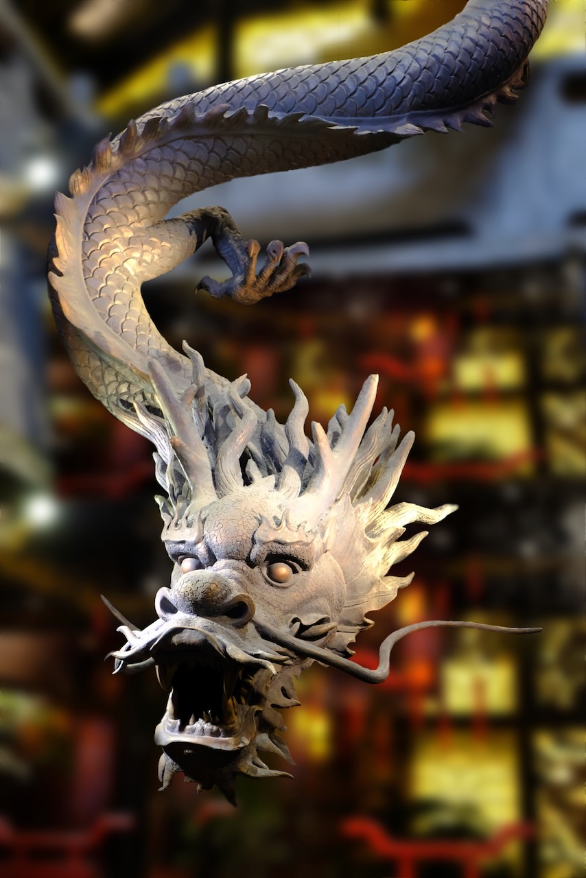 Carved dragon sculpture hanging from a temple ceiling