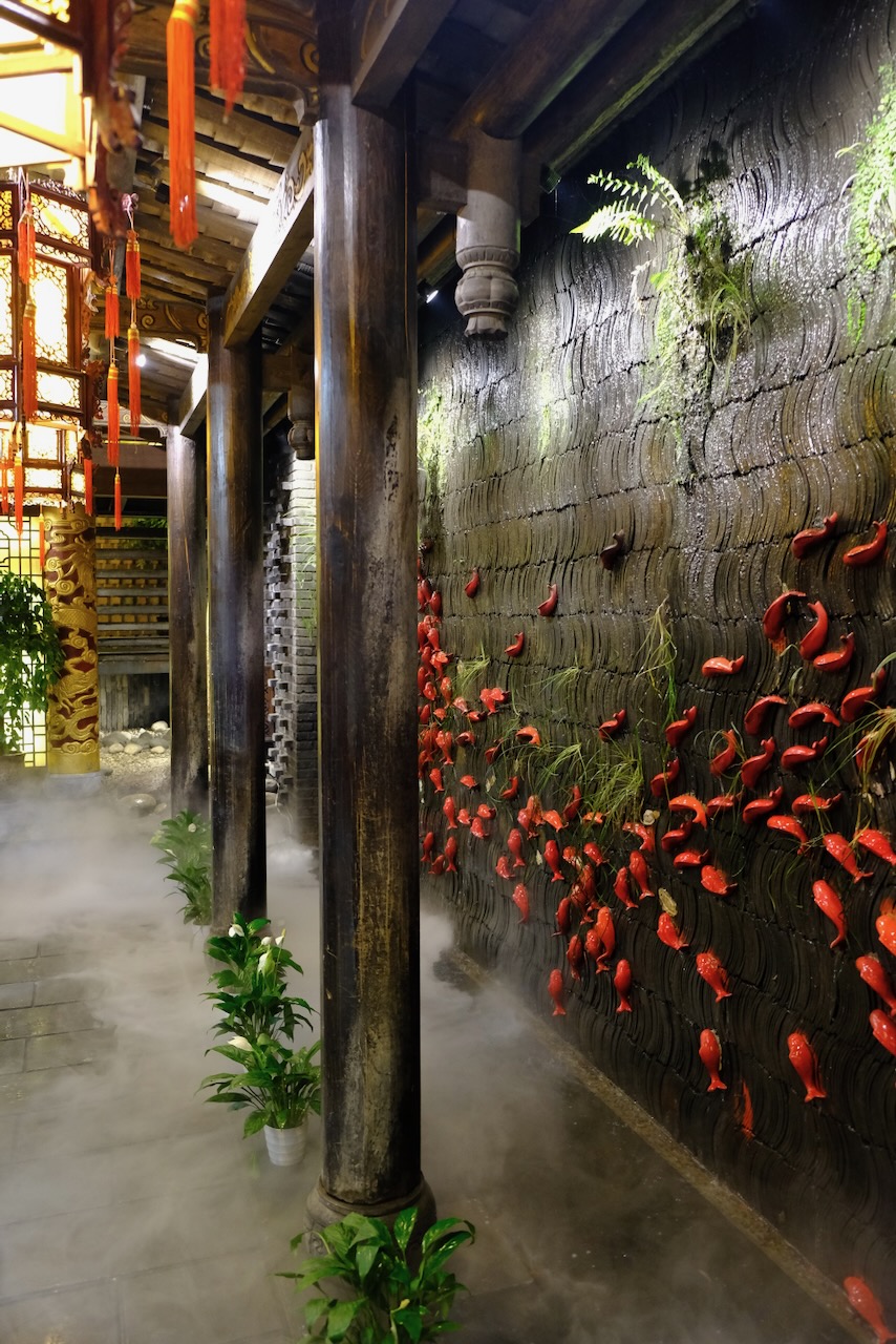 Misty courtyard with red ceramic fish on a tiled wall