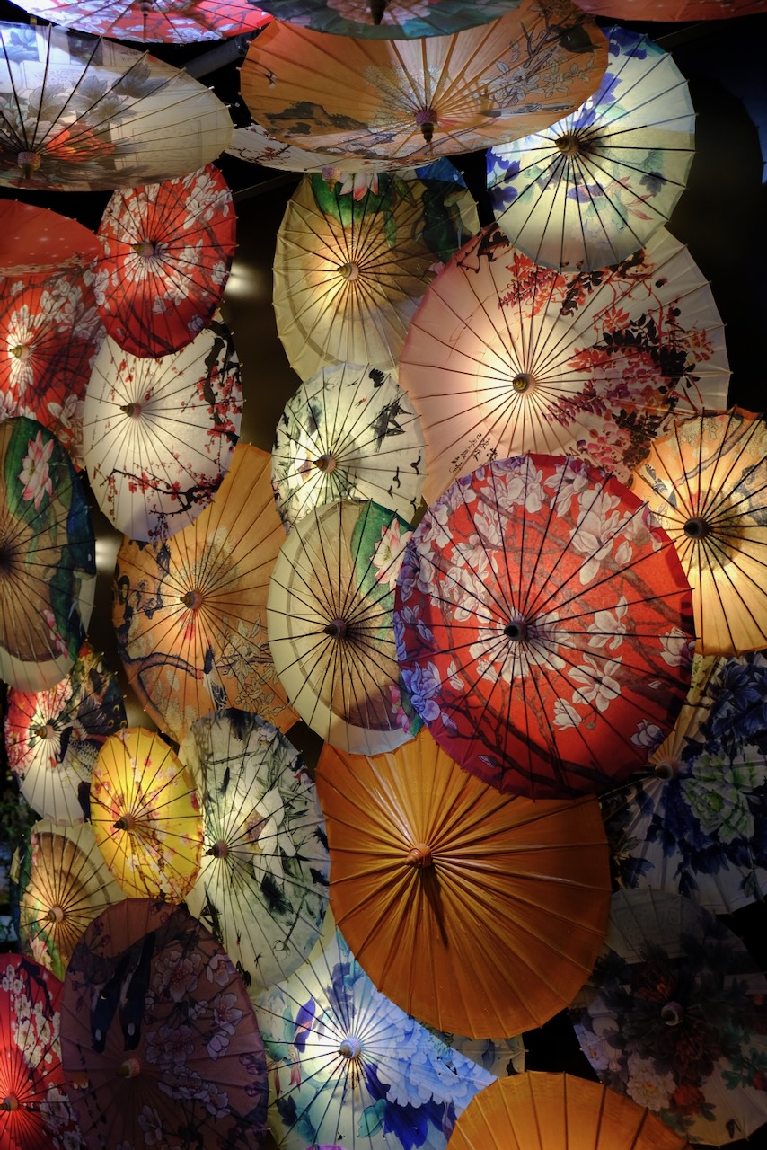 Painted paper umbrellas arranged as a glowing ceiling