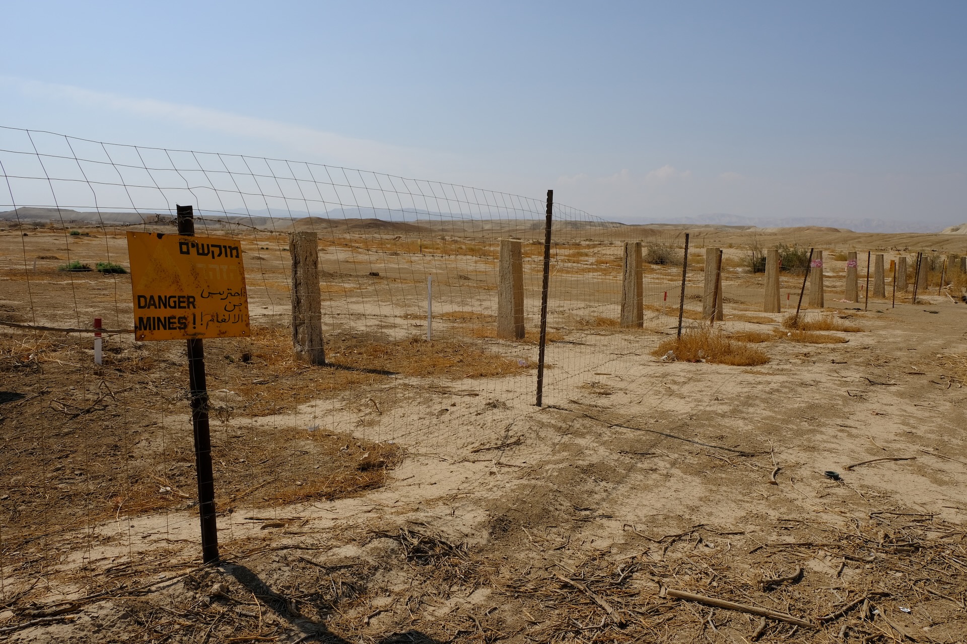 Fence with warning sign marking a restricted area in a dry Middle Eastern landscape